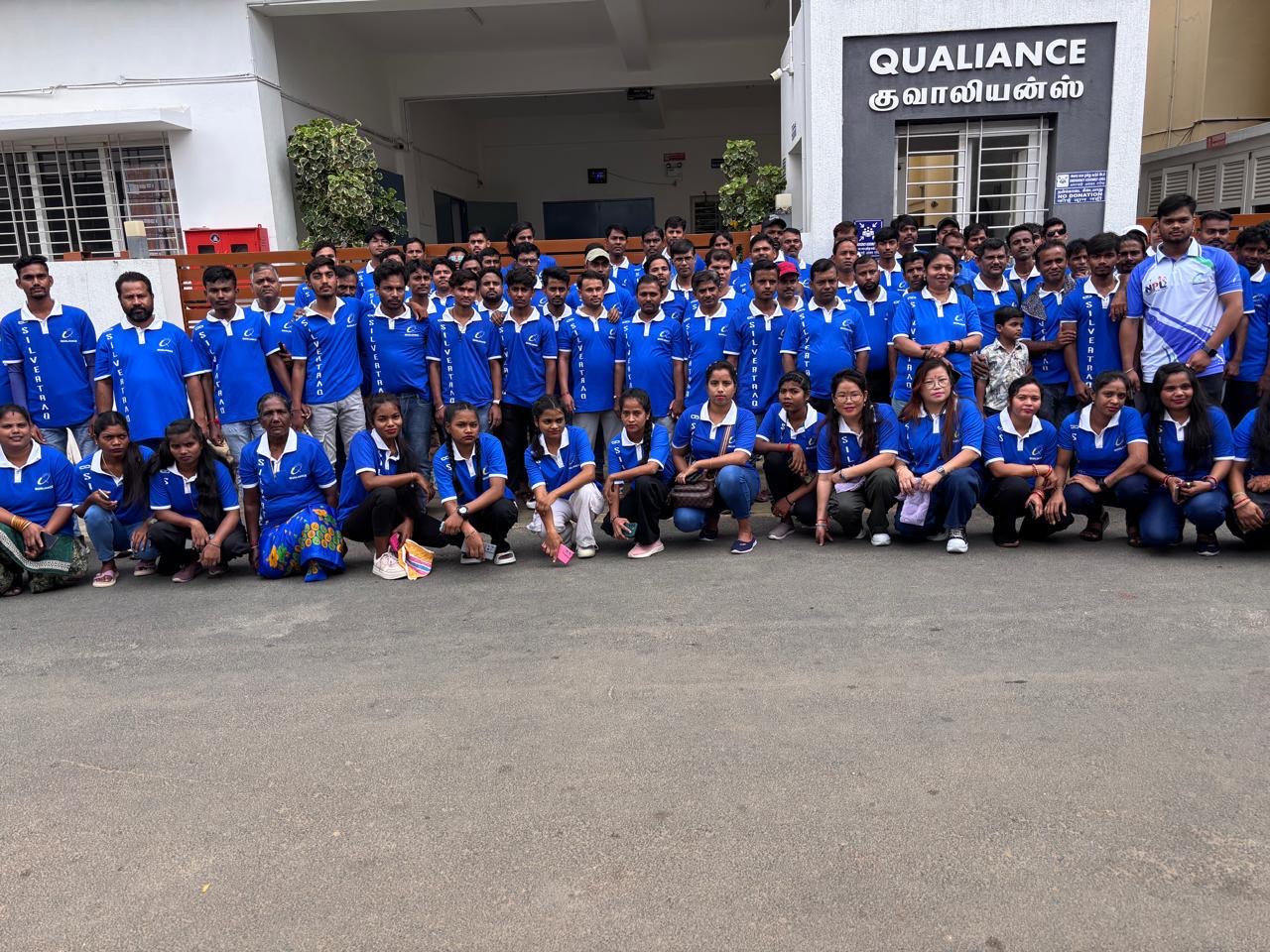 Team Qualiance — full squad in blue jerseys outside the factory